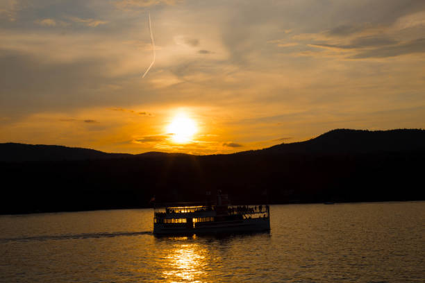 Afternoon sunset by the lake with a boat passing by. Mountain range in the background.