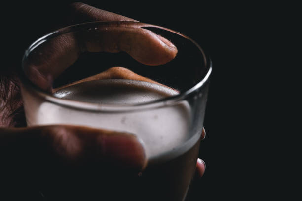hand holding a glass filled with mochaccino at the bedroom window, mochaccino in the morning.