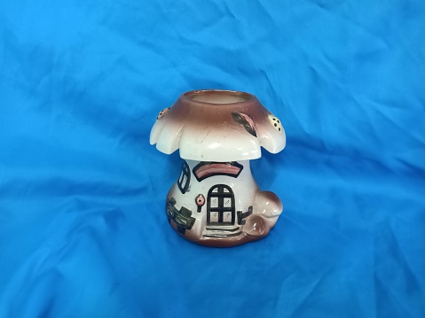 Handmade ceramic figurine of a mushroom  house   pen holder on a blue background.photo taken in malaysia