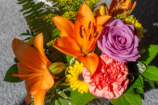 This image shows a macro texture background of bright flowers in an indoor florist arrangement, featuring a lily, rose and carnation.