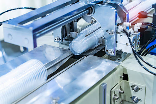 Stack of polypropylene food containers cup on conveyor belt of automatic plastic injection molding machine,automated technology concept