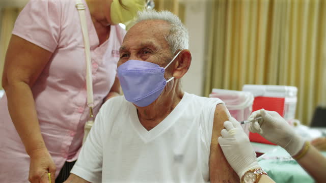 Elderly men receive vaccination services.