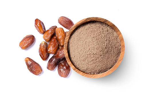 Date fruit powder in wooden bowl with dry dates fruits isolated on white background. Top view, flat lay.