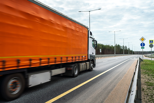 Orange heavy truck riding at multiple lane highway
