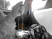 Religious Balinese young woman with traditional kebaya clothes praying rosary in the car in black and white.