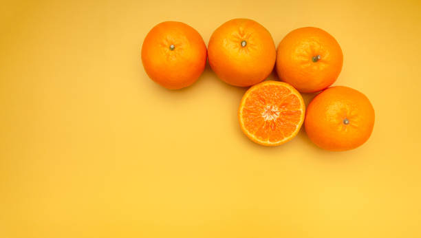 istock Pile of fresh oranges whole and half fruit on a yellow background with copy space for text 1689923552