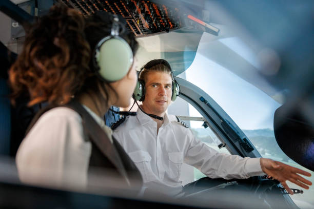 pilot explaining how a flight simulator works to a female student during a training session - avionics flying training cockpit imagens e fotografias de stock