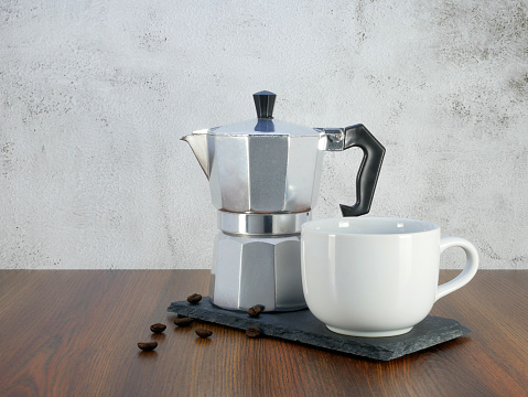 Coffee maker moka pot and a cup on wooden table.