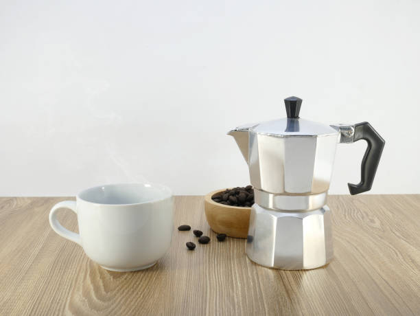 istock Coffee maker moka pot and a cup on wooden table. 1689986941
