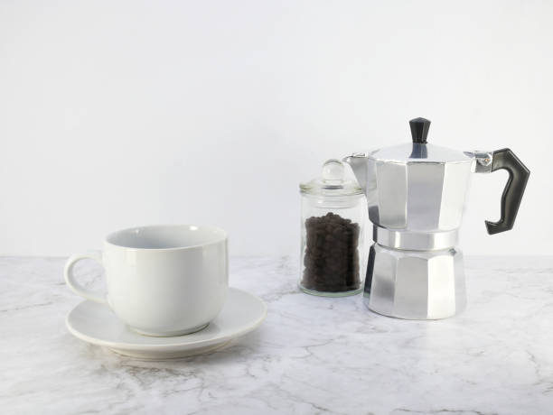 istock Coffee maker moka pot and a cup on marble  table. 1689986942