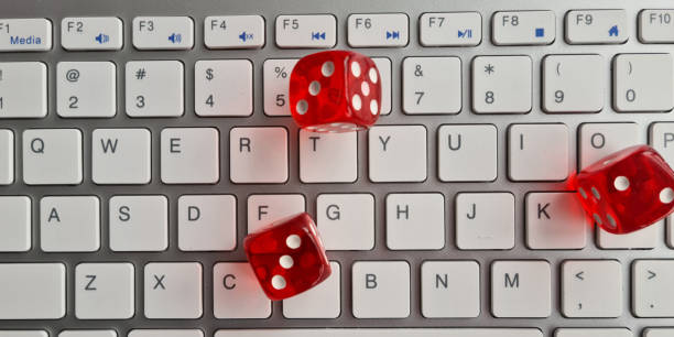 istock Red dice lying on white keyboard as online casino concept 1689990391