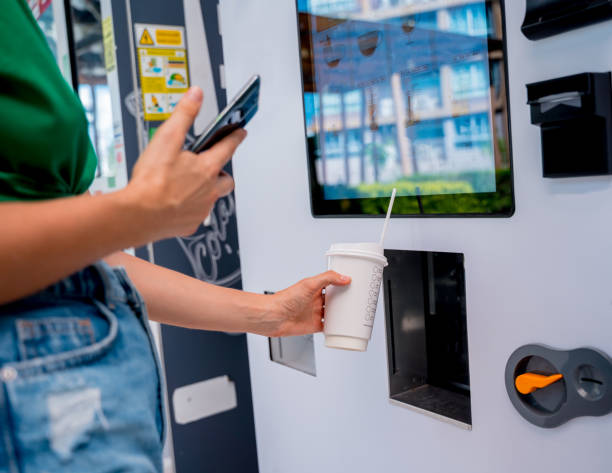 istock Young woman paying for coffee at vending machine using contactless method of payment 1689992245