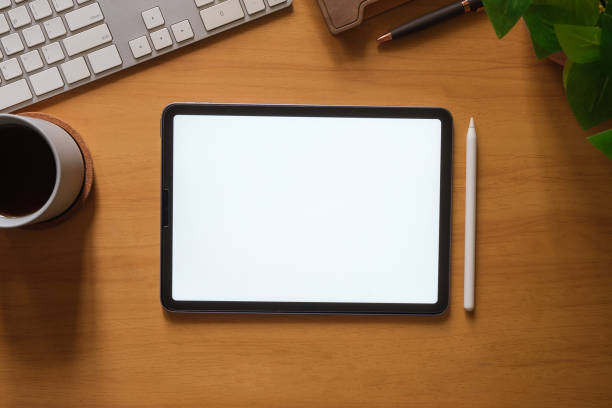 istock Digital tablet with blank screen, coffee cup, stationery and keyboard on wooden table. 1690011555