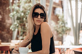 Beautiful blonde model woman, fashionable in a black suit, posing in a cafe