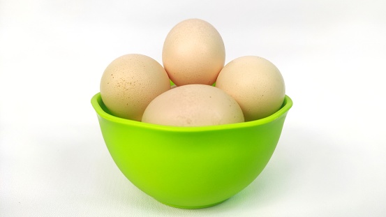 A bowl of raw egg on the green plastic bowl isolated on white background