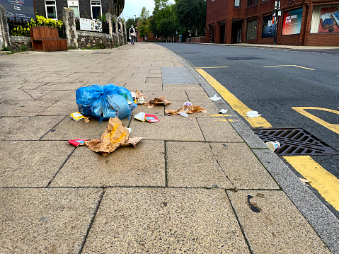 Discarded fast food containers and a blue plastic bag on a street in central Norwich