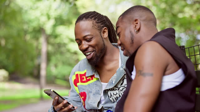 African-American gay couple using smart phone and talking