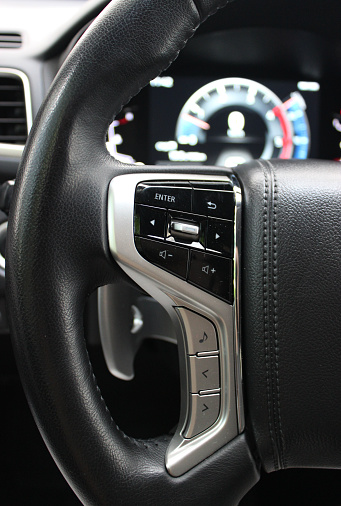 Control Panel On A Steering Wheel And Blurred Digital Dashboard Inside Modern Vehicle