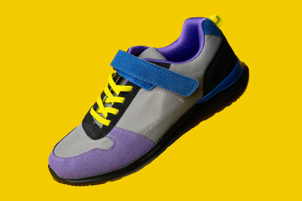 istock Violet-blue female sneakers on yellow studio background 1690114025