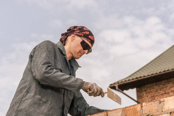 An experienced worker works on the construction of a brick house