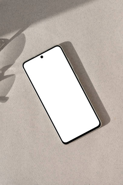istock Blank mobile phone mockup with empty white screen on neutral beige background with aesthetic natural sun light shadow. Minimal business branding identity design template, flat lay 1690127910
