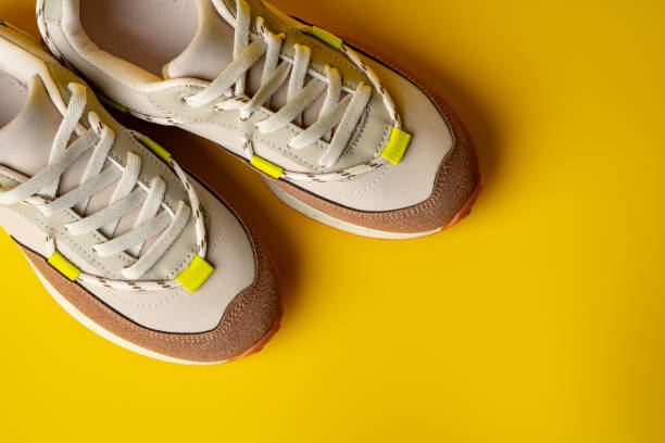 istock Beige sport running shoes on yellow studio background 1690138100