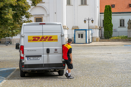 Delivery by DHL. White minibus on the street, delivery of settlements and documents. Poland, Warsaw - July 26, 2023.