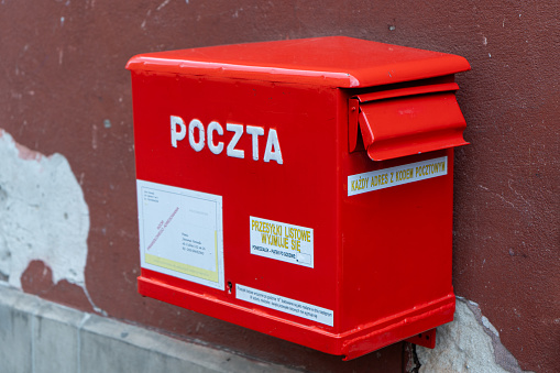 Polish red mailbox on the street. Box for letters and correspondence delivery. Warsaw, Poland - July 23, 2023.
