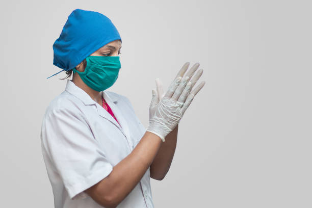 Close up of a indian female nurse or doctor wearing surgical mask getting ready for surgery in operation theater. Sterilizing hands Close up of a indian female nurse or doctor wearing surgical mask getting ready for surgery in operation theater. Sterilizing hands Medical Scrub Caps stock pictures, royalty-free photos & images