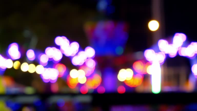 Blurred motion lights from the rotating machines move around in the theme park festival at night.