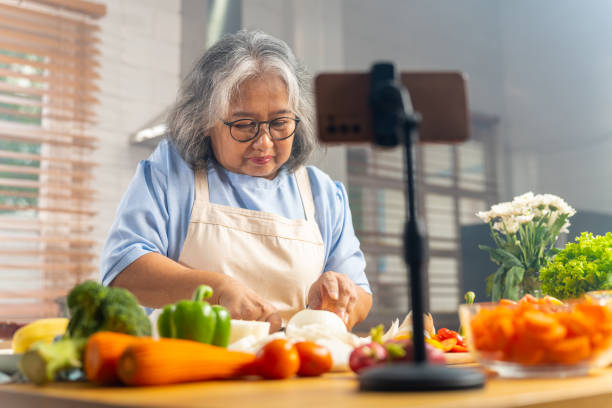 istock Grandmother live streaming cooking meal in the kitchen. 1690211682