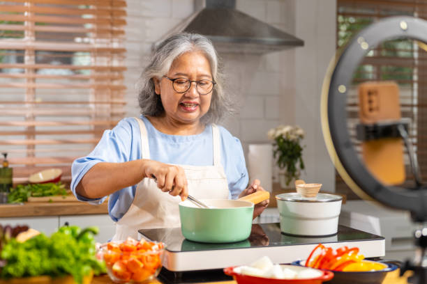 istock Grandmother live streaming cooking meal in the kitchen. 1690213307