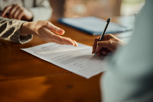 Close up of unrecognizable black woman signing a contract during a meeting with her agent in the office. Copy space.