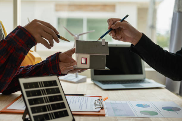 istock Two Caucasian engineers and architects work together in office with wind turbine and solar panels on table, renewable energy installation concept 1690228739