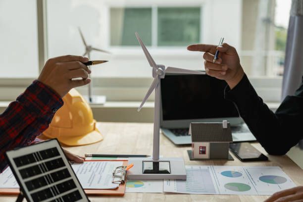 istock Two Caucasian engineers and architects work together in office with wind turbine and solar panels on table, renewable energy installation concept 1690229294