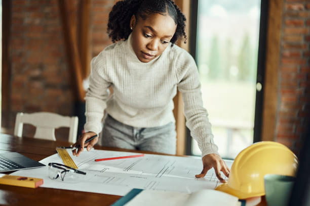 istock African American female architect examining blueprints in the office. 1690229321