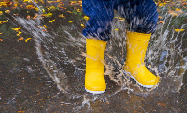 istock Kid jumping in the puddle. Rubber waterproof yellow boots. 1690263121