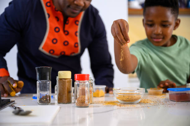 istock Son sprinkles spices into bowl preparing food with father 1690263671