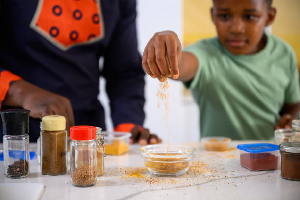 istock Boy sprinkles spices into bowl preparing food with father 1690263682
