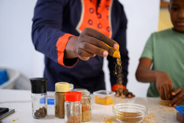 Close up father adding colourful spice to mixing bowl