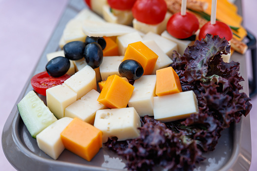 Appetizer tray on restaurant table, cheese cubes, black olives and cherry tomatoes, radicchio lettuce garnish