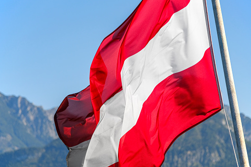 The Austrian national flag waves in the wind against the backdrop of the Alps.