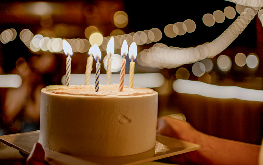 Birthday cake with candles with bright bokeh lights on the background.