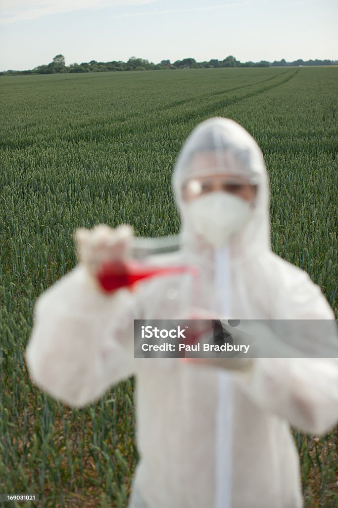 Wissenschaftler in schützende Kleidung gießen Flüssigkeit in Becherglas - Lizenzfrei Genmanipulation Stock-Foto