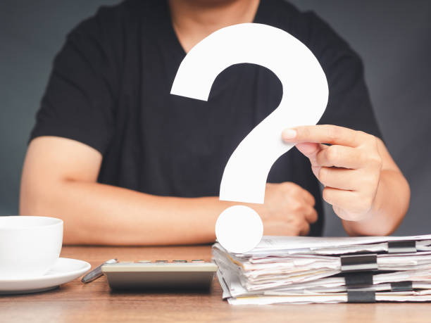 istock A young man in a black casual is holding a white question mark symbol while sitting at the table 1690310265