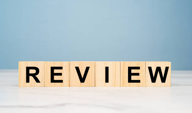 istock Wooden cubes with the letters REVIEW on a table with light blue background 1690311901