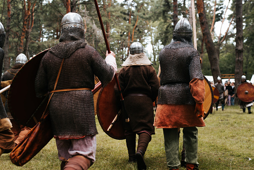 Back view of attacking medieval warriors in the forest.