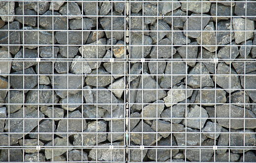 Building wall stacked pebbles covered with wire mesh