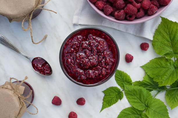 istock Flat lay composition with glass bowl of raspberry jam on white marble table. Top view. 1690342768