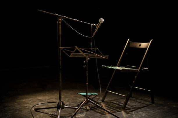 istock Dark empty room with a microphone and a chair on a stage 1690358665
